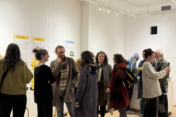 People gathered in a room, stood, posters for the group are on the walls around them