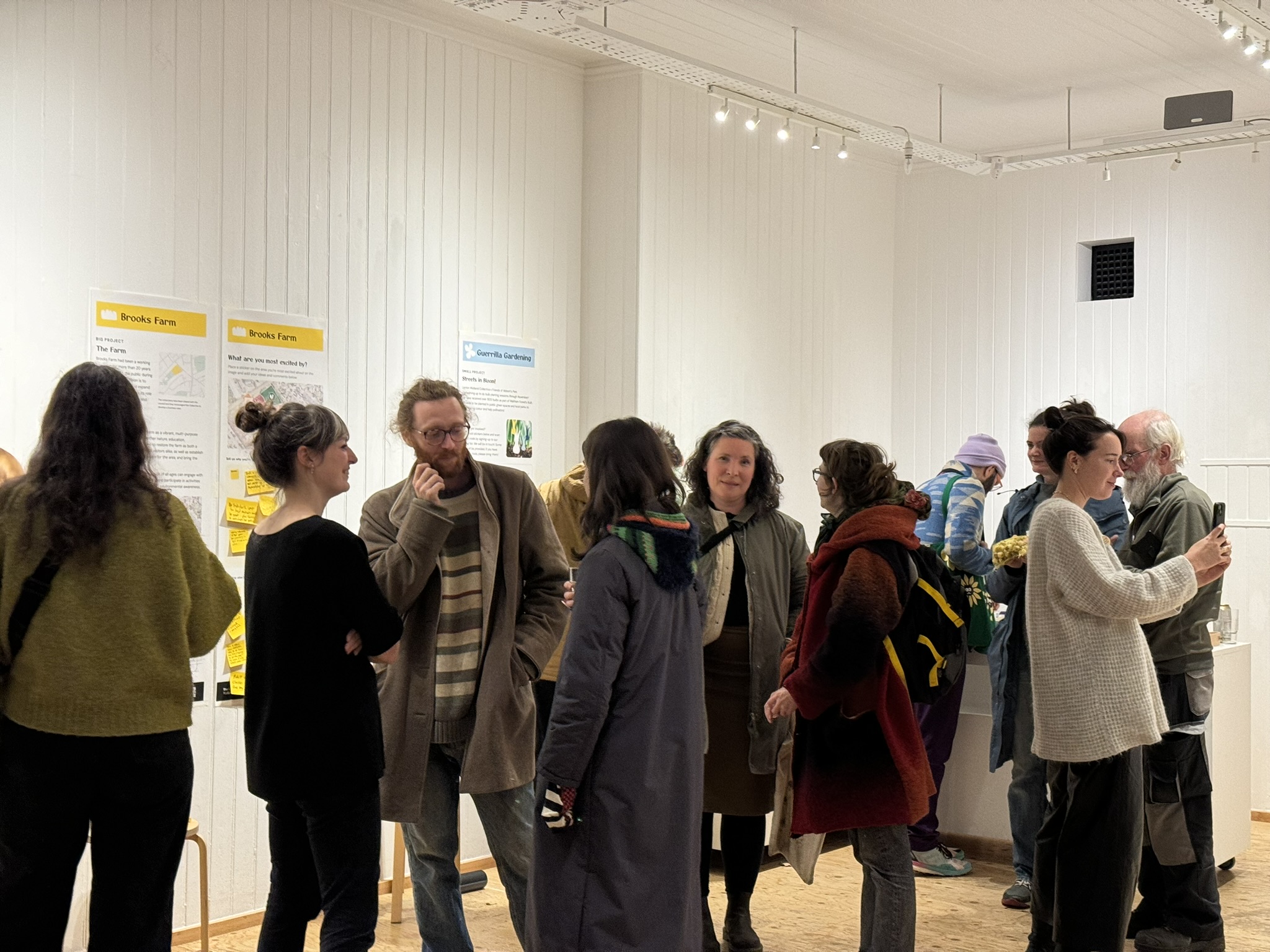People gathered in a room, stood, posters for the group are on the walls around them