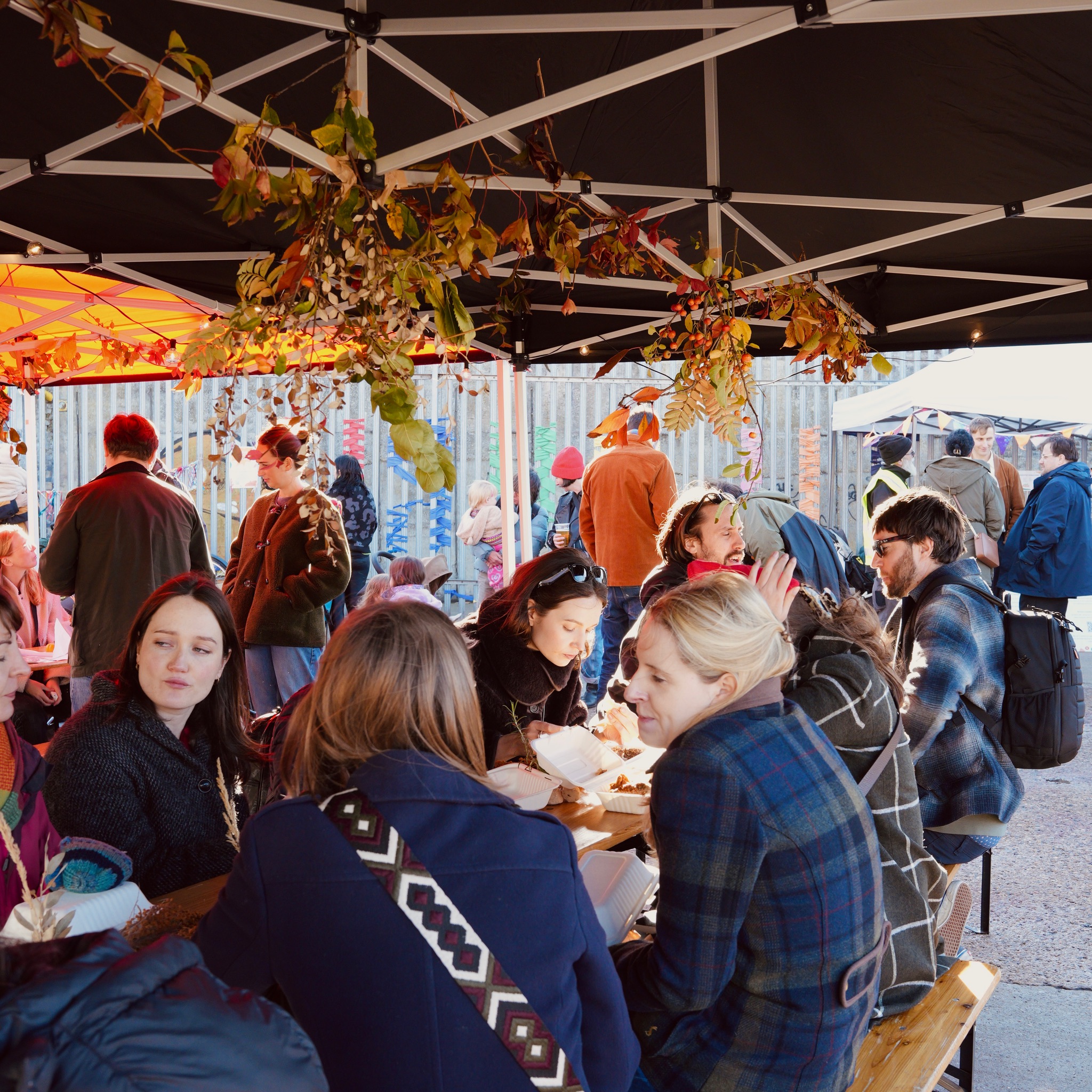 A long table with people eating outside - the community feast