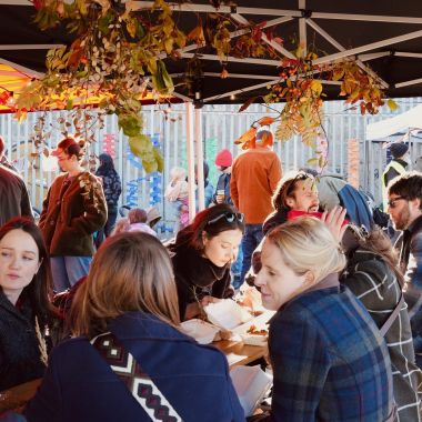 A long table with people eating outside - the community feast